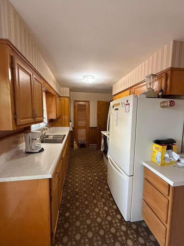 1721 W Union St, Lancaster, OH 43130 - kitchen featuring brown cabinetry, freestanding refrigerator, wallpapered walls, light countertops, and a sink