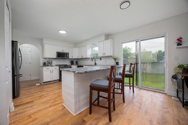 380 Oak Village Dr, Columbus, OH 43207 - kitchen with stainless steel appliances, a breakfast bar area, tasteful backsplash, white cabinets, and a textured ceiling