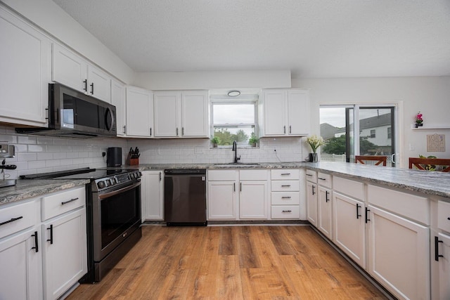 380 Oak Village Dr, Columbus, OH 43207 - kitchen featuring stainless steel appliances, a sink, backsplash, plenty of natural light, and a textured ceiling