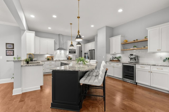 kitchen with backsplash, a sink, wine cooler, stainless steel appliances, and wall chimney exhaust hood