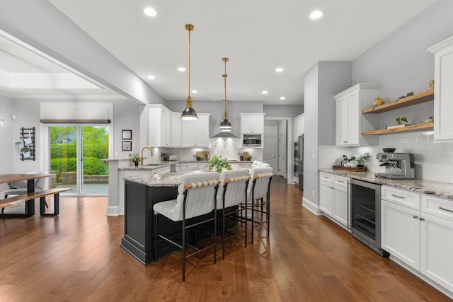 kitchen featuring a breakfast bar, a sink, beverage cooler, stainless steel microwave, and tasteful backsplash