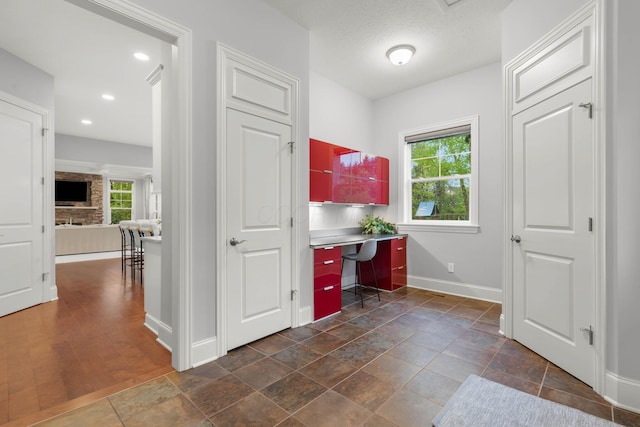 office area featuring recessed lighting, baseboards, a stone fireplace, and built in study area