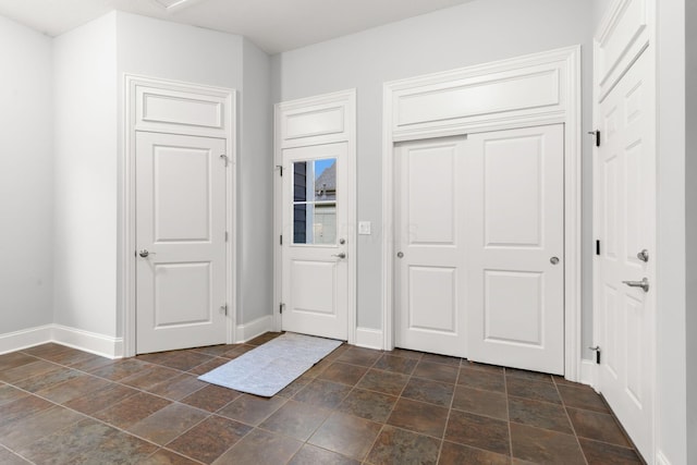 entrance foyer featuring baseboards and stone finish floor