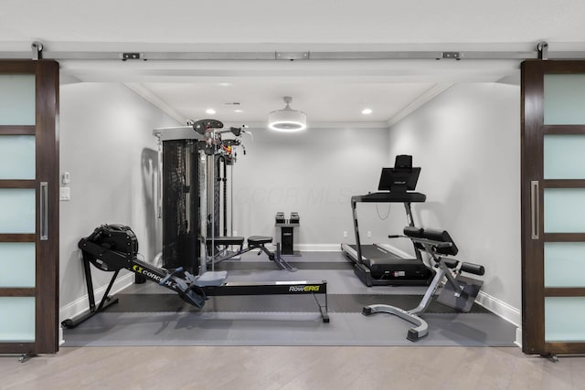 workout area with baseboards, ornamental molding, and a barn door