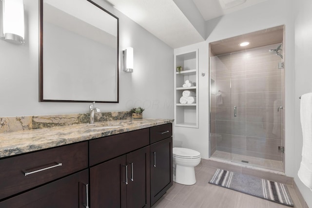 bathroom with vanity, toilet, built in shelves, and a stall shower