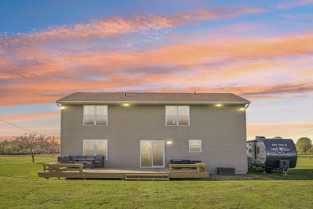 back of property at dusk featuring a deck, a yard, and an outdoor hangout area