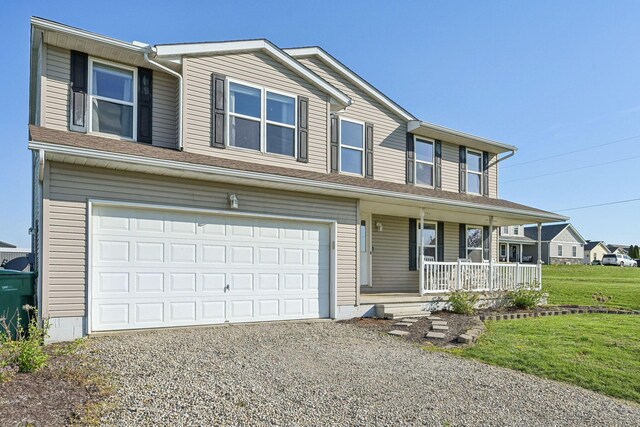 traditional-style house featuring a garage, a porch, gravel driveway, and a front lawn