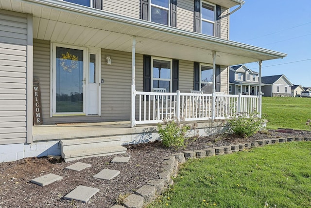 doorway to property featuring a porch and a yard