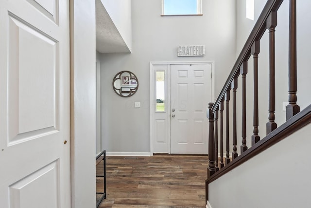 foyer entrance featuring a high ceiling, stairway, wood finished floors, and plenty of natural light