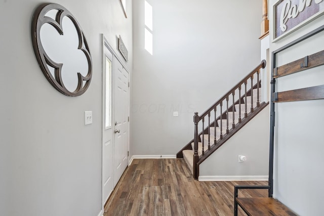 foyer with baseboards, wood finished floors, and stairs