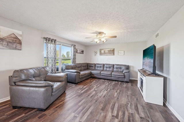 living room featuring a textured ceiling, visible vents, ceiling fan, baseboards, and dark wood-type flooring