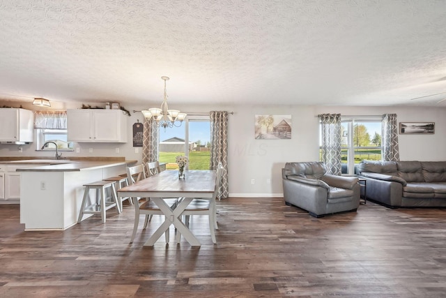dining space with plenty of natural light, a textured ceiling, a chandelier, and dark wood finished floors