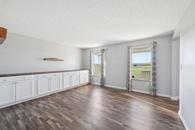 spare room featuring dark wood-style floors, baseboards, and a textured ceiling