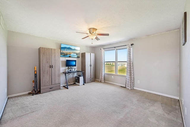 carpeted empty room with a textured ceiling, ceiling fan, and baseboards