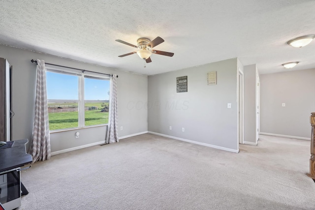 carpeted spare room with a textured ceiling, ceiling fan, and baseboards