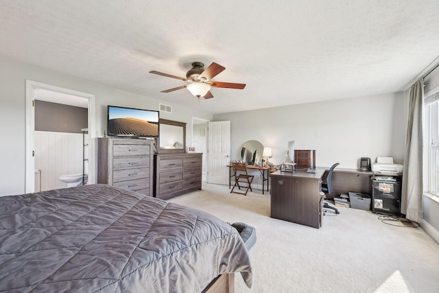 bedroom with ceiling fan, visible vents, light carpet, a textured ceiling, and ensuite bathroom