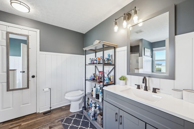 full bathroom with wood finished floors, wainscoting, toilet, vanity, and visible vents