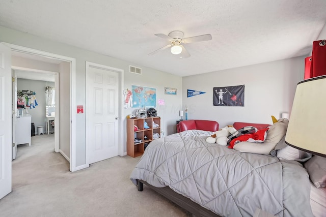 bedroom featuring light colored carpet, ceiling fan, baseboards, visible vents, and a textured ceiling