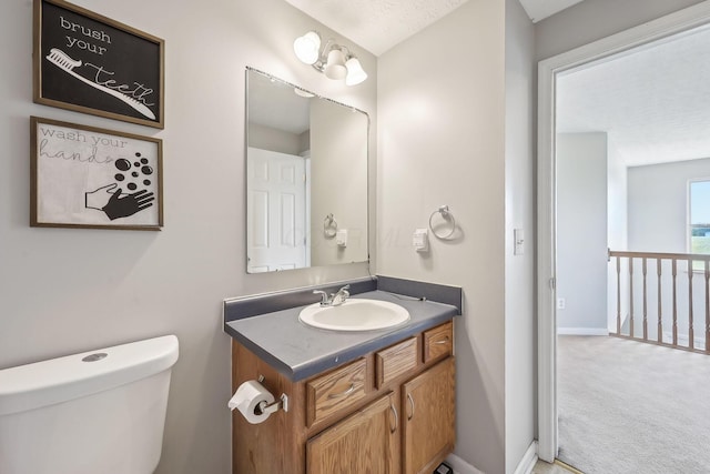 half bathroom with baseboards, toilet, and vanity