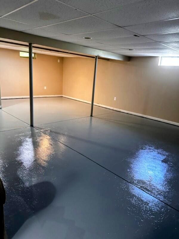 below grade area featuring a paneled ceiling and baseboards