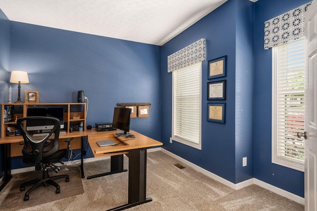 carpeted office featuring a wealth of natural light, visible vents, and baseboards