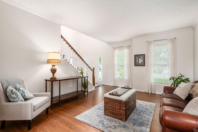living area with stairway, baseboards, ornamental molding, a textured ceiling, and wood finished floors