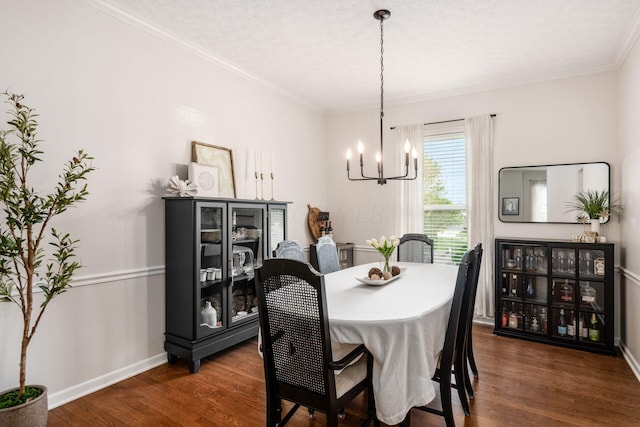 dining room featuring dark wood finished floors, baseboards, ornamental molding, and a notable chandelier