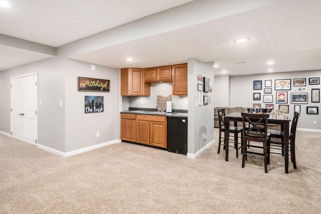 kitchen featuring baseboards, light carpet, and black dishwasher