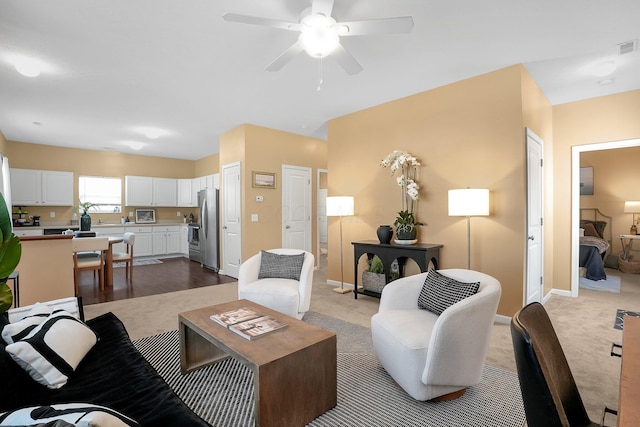 living room with ceiling fan, baseboards, and dark carpet