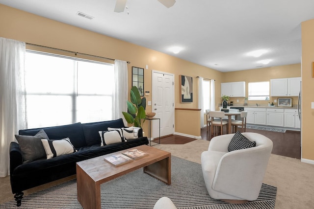 living room featuring baseboards, ceiling fan, and visible vents