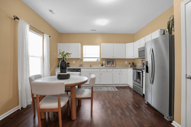 kitchen featuring dark wood-style flooring, visible vents, appliances with stainless steel finishes, light countertops, and white cabinetry