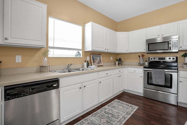 kitchen with white cabinets, a sink, light countertops, stainless steel appliances, and dark wood-style floors