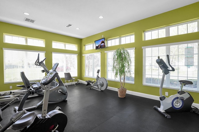 exercise room with baseboards, a wealth of natural light, and visible vents