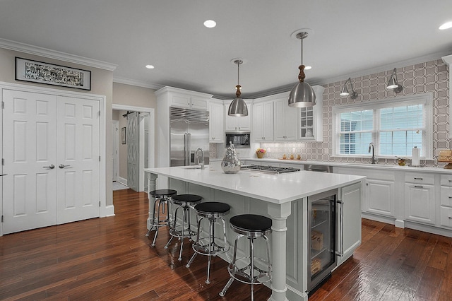 2443 Shepherd Ct, Powell, OH 43065 - kitchen with built in appliances, ornamental molding, a sink, a kitchen breakfast bar, and a kitchen island with sink