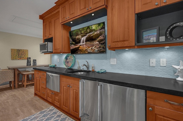 2443 Shepherd Ct, Powell, OH 43065 - kitchen with appliances with stainless steel finishes, a sink, brown cabinetry, dark countertops, and ornamental molding
