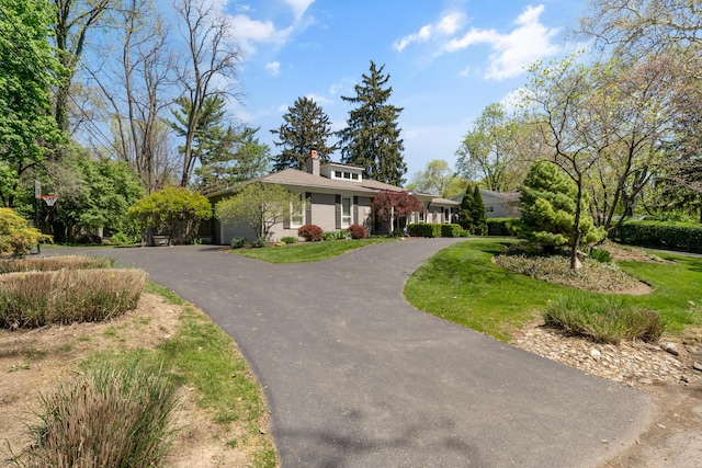 view of front of property with a garage, curved driveway, and a chimney