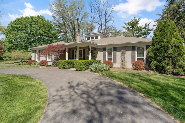 view of front of home with brick siding, a front yard, and a chimney