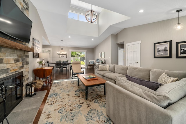 living room featuring a high ceiling, wood finished floors, a chandelier, and a fireplace