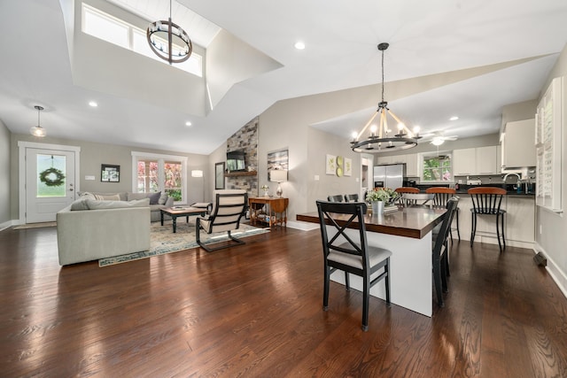 dining space with dark wood-style flooring, baseboards, an inviting chandelier, and high vaulted ceiling