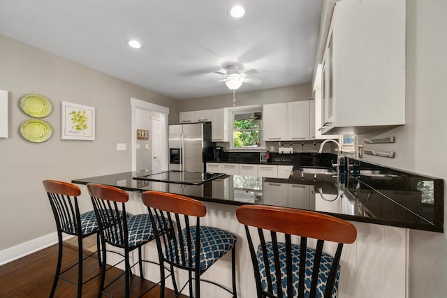 kitchen with ceiling fan, dark wood-style floors, stainless steel refrigerator with ice dispenser, black electric cooktop, and a sink
