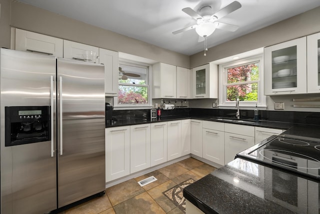 kitchen with white cabinetry, a sink, stainless steel fridge, and a healthy amount of sunlight