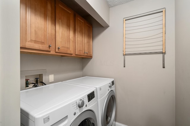 clothes washing area with washing machine and dryer and cabinet space