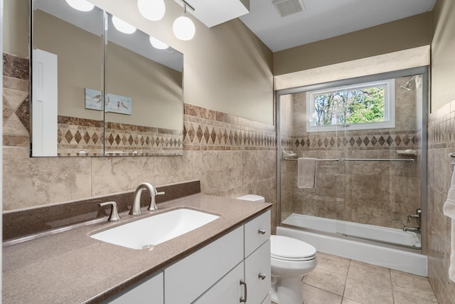 bathroom featuring visible vents, tile walls, tile patterned floors, vanity, and toilet