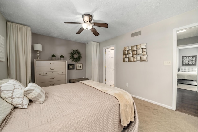 carpeted bedroom with visible vents, a ceiling fan, baseboards, and a textured ceiling