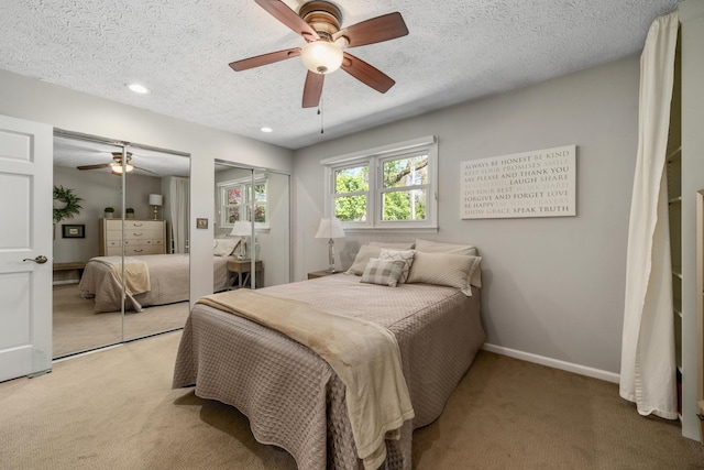 bedroom featuring baseboards, ceiling fan, two closets, and light carpet