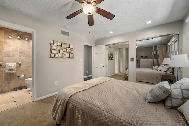 carpeted bedroom with multiple closets, recessed lighting, a textured ceiling, and visible vents