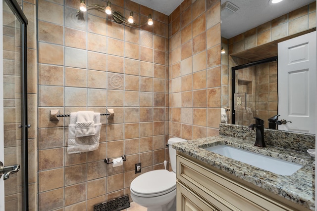 bathroom with visible vents, vanity, toilet, tile walls, and a shower stall