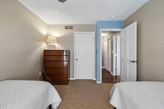 carpeted bedroom featuring baseboards, a textured ceiling, and visible vents
