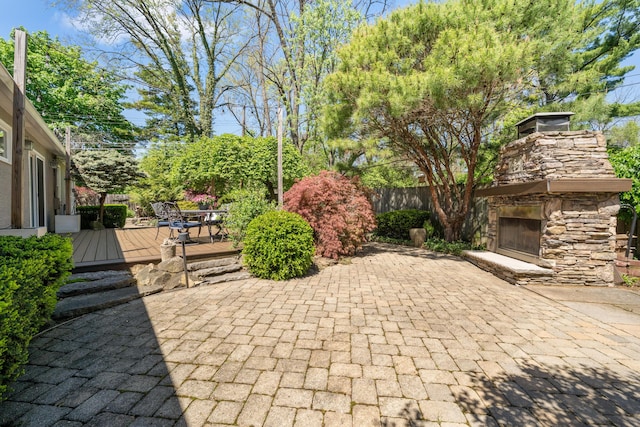 view of patio / terrace featuring an outdoor stone fireplace, fence, and a wooden deck