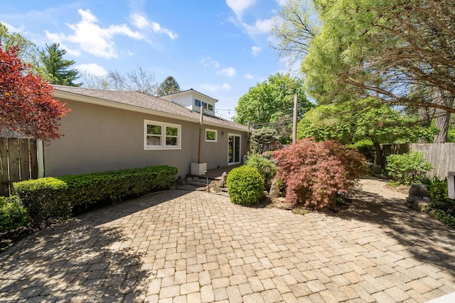 back of property with a patio, fence, and stucco siding